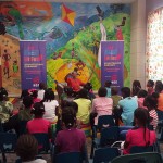 Thelma Perkins Displays a miniature lion to Children at Bocas Lit Storytelling Caravan Tobago.